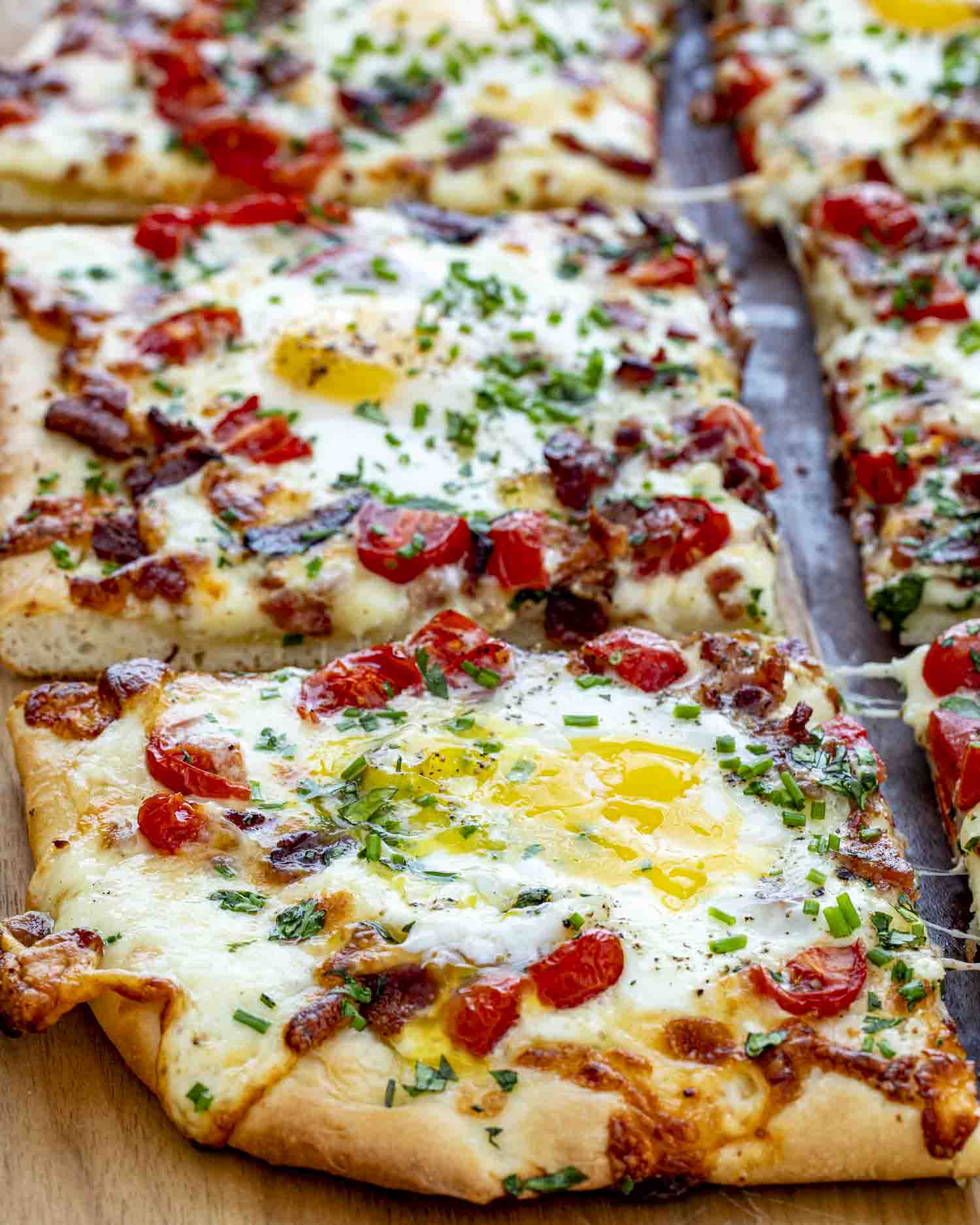 Breakfast Pizza Golden breakfast pizza topped with sunny eggs, crispy bacon, melted cheese, juicy tomatoes, and fresh herbs on fluffy crust.