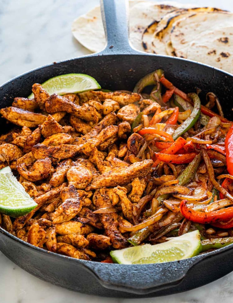 chicken fajitas in a skillet garnished with lime wedges