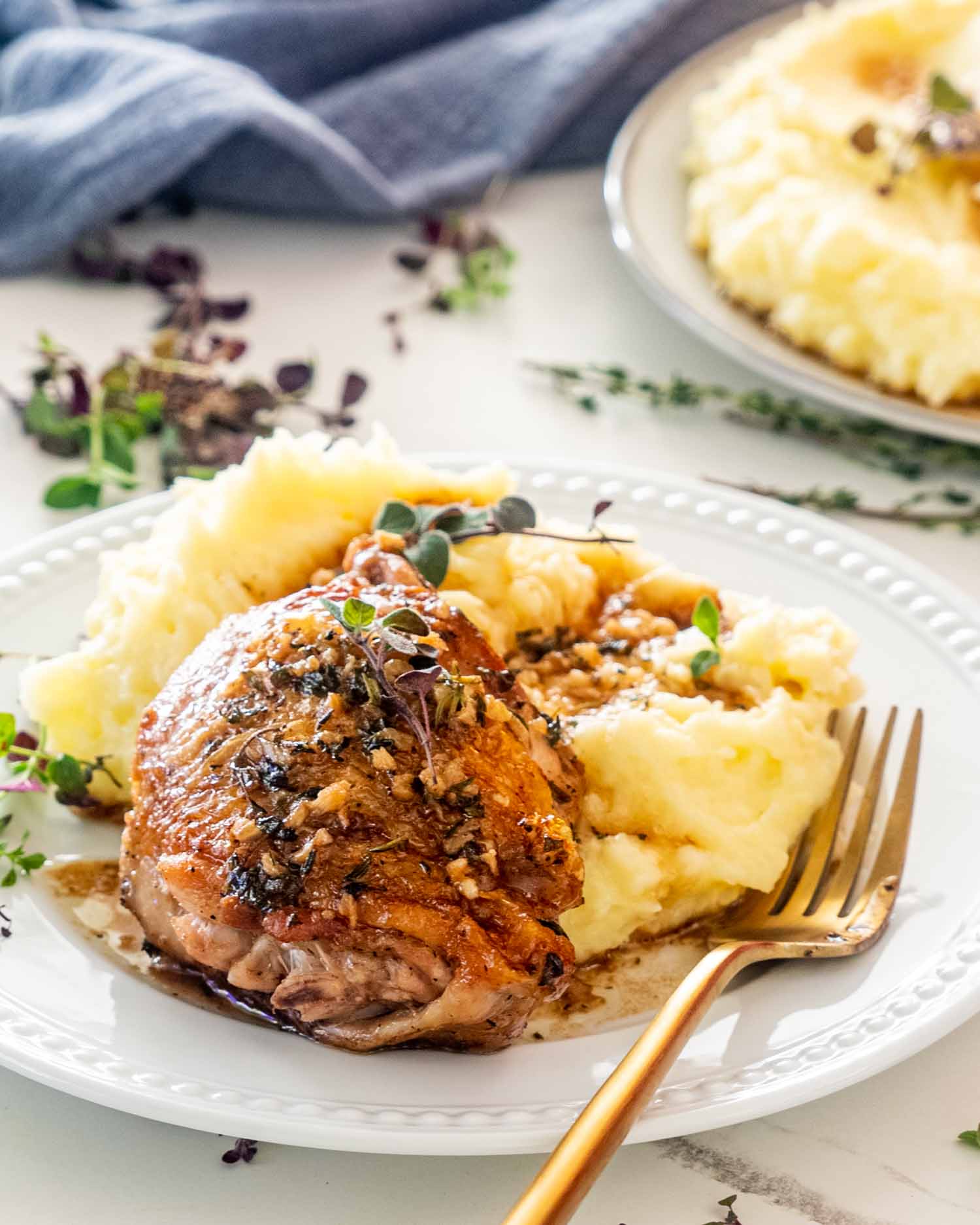 a chicken thigh in garlic and herb sauce over a bed of mashed potatoes.