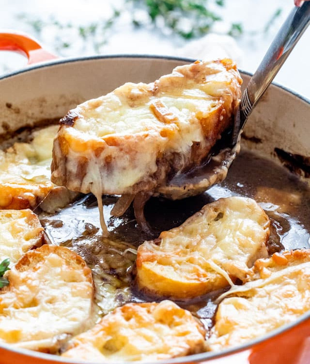 a ladle taking a scoop of french onion soup from the pot