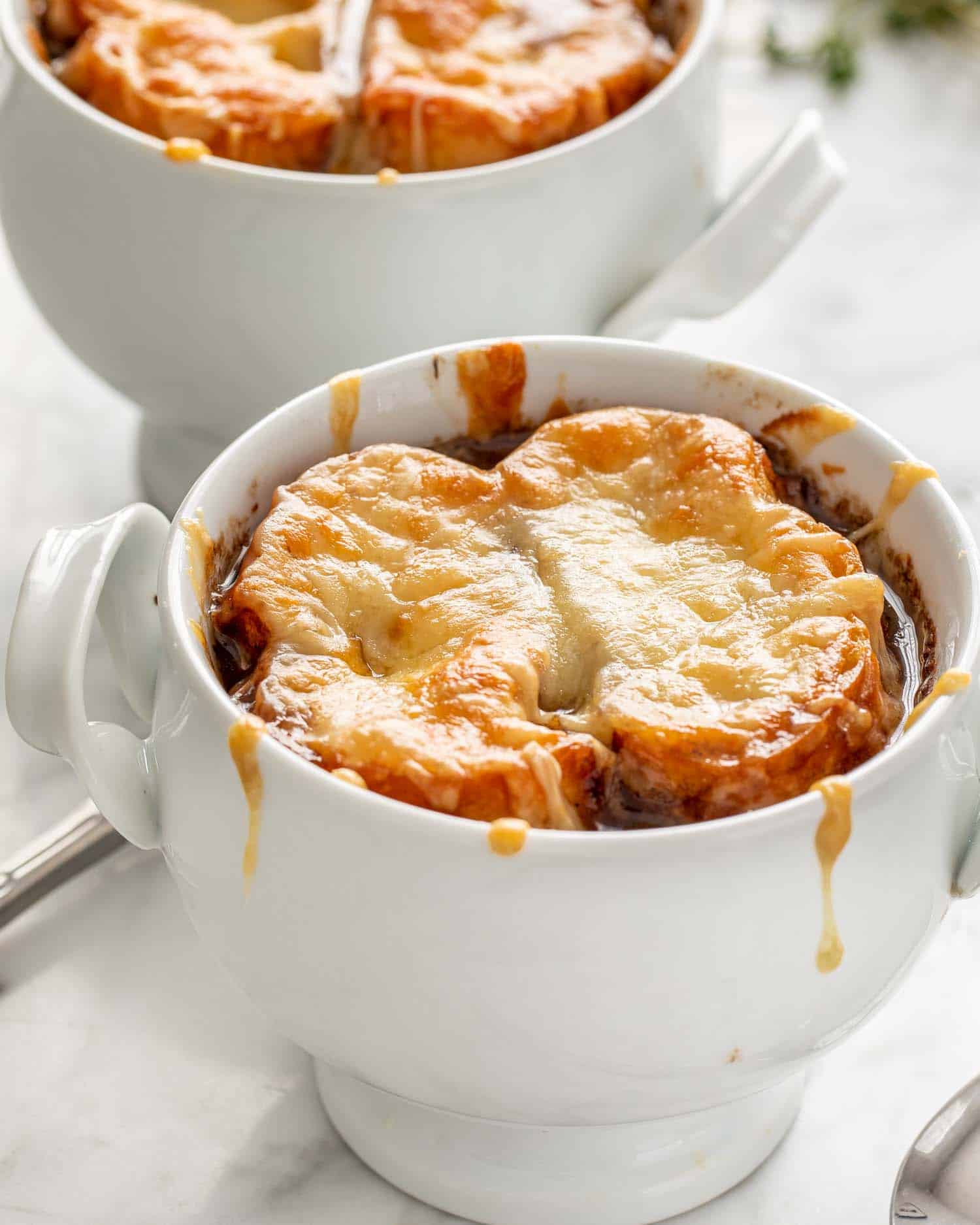 two white bowls with french onion soup.