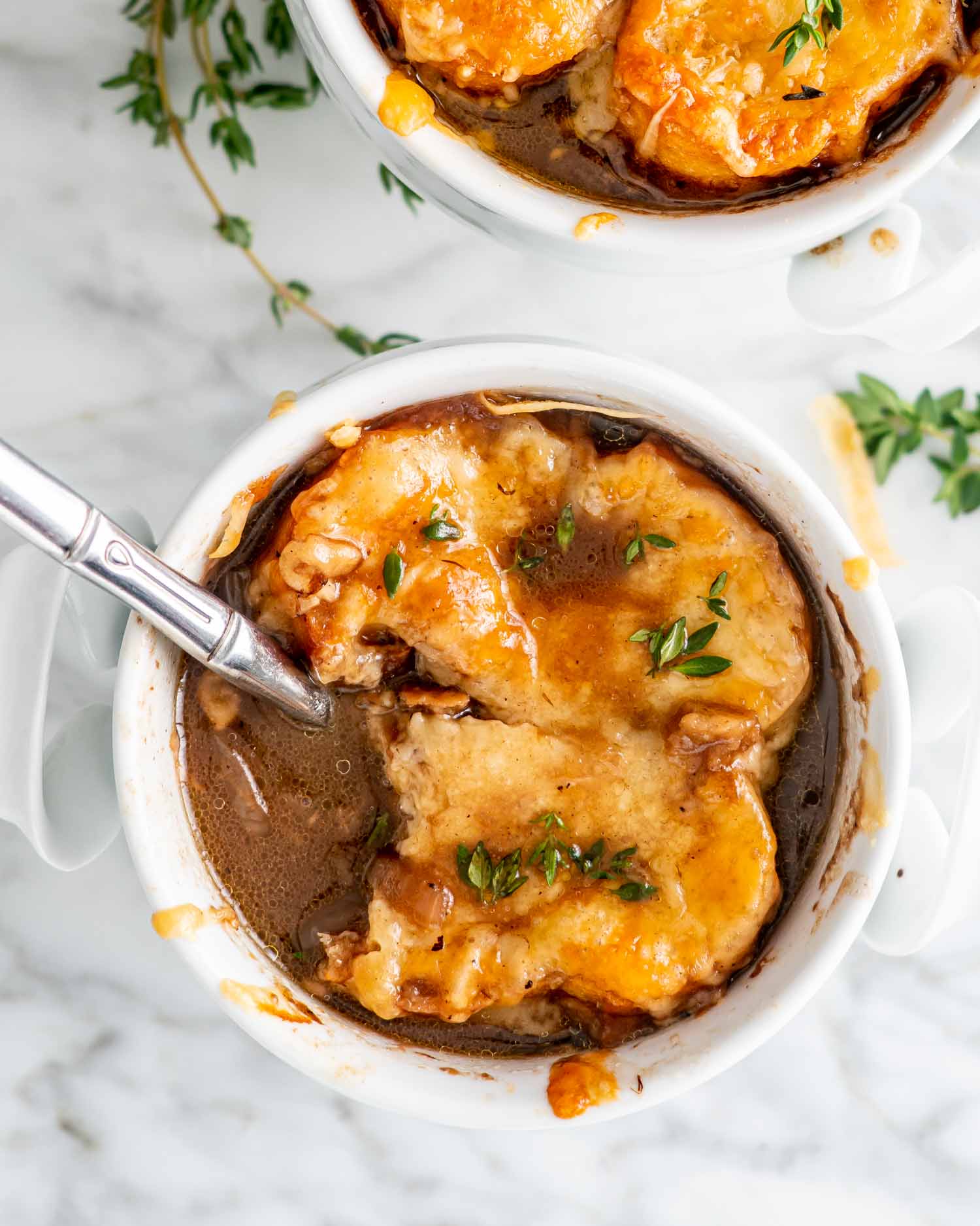 two white bowls with french onion soup.
