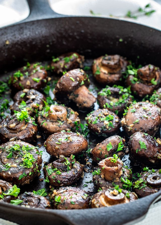 a skillet filled with garlic butter mushrooms topped with parsley
