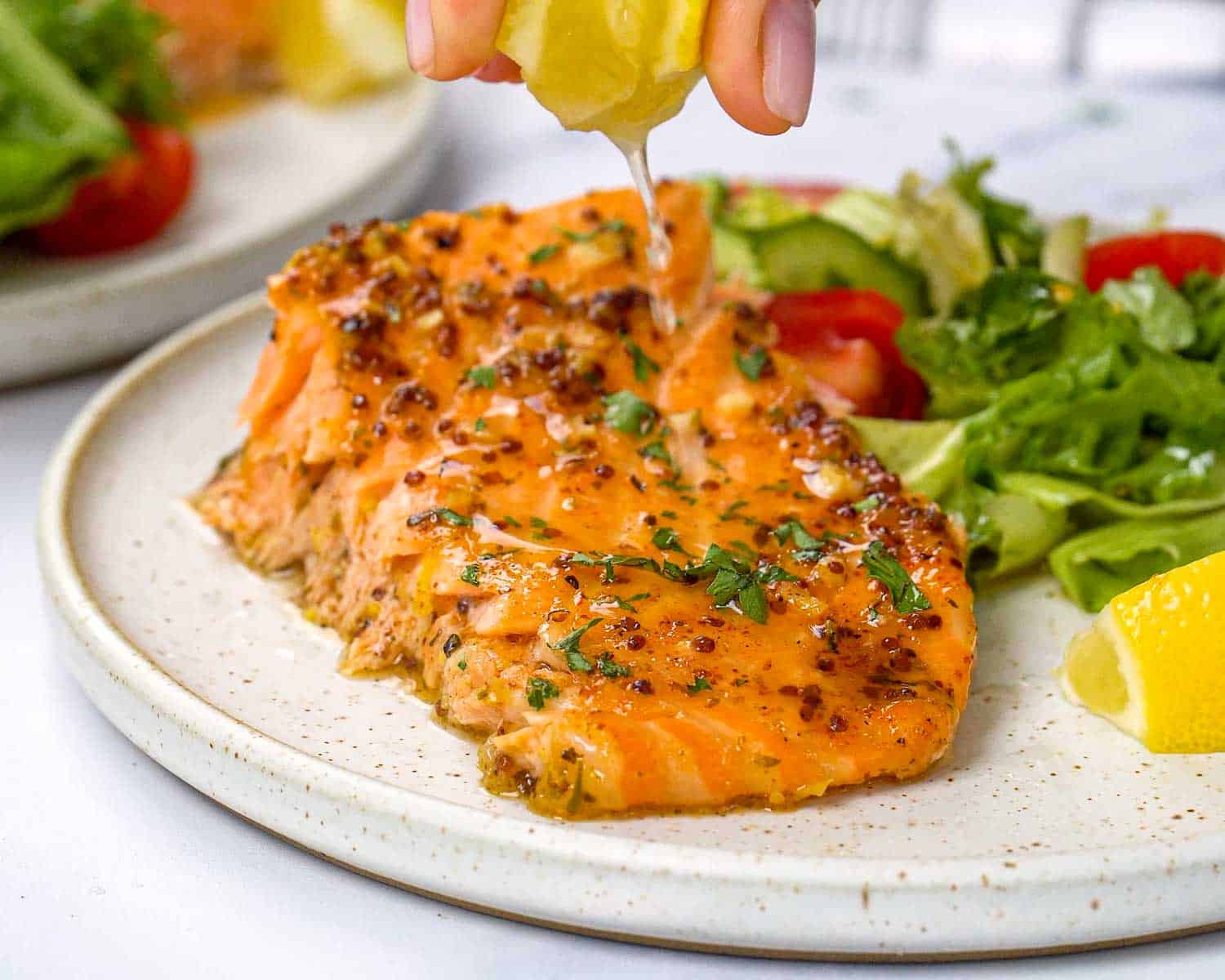 Baked honey mustard salmon fillet served with green salad and lemon wedge, topped with glossy honey mustard sauce.