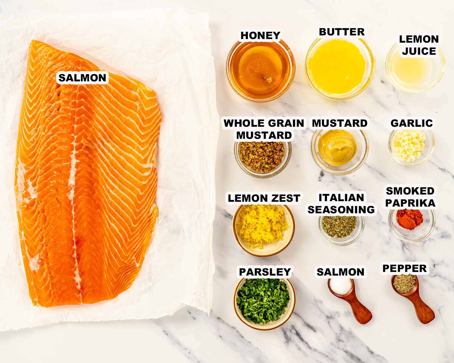 Raw salmon fillet with honey, butter, lemon juice, mustard, garlic, lemon zest, parsley, and spices arranged on marble surface.