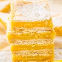 a few lemon bars stacked on top of each other on parchment paper.