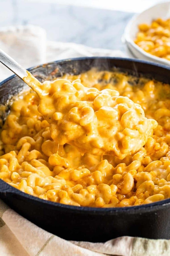 a spoon scooping out some mac and cheese from a skillet.