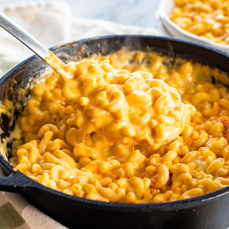 a spoon scooping out some mac and cheese from a skillet.