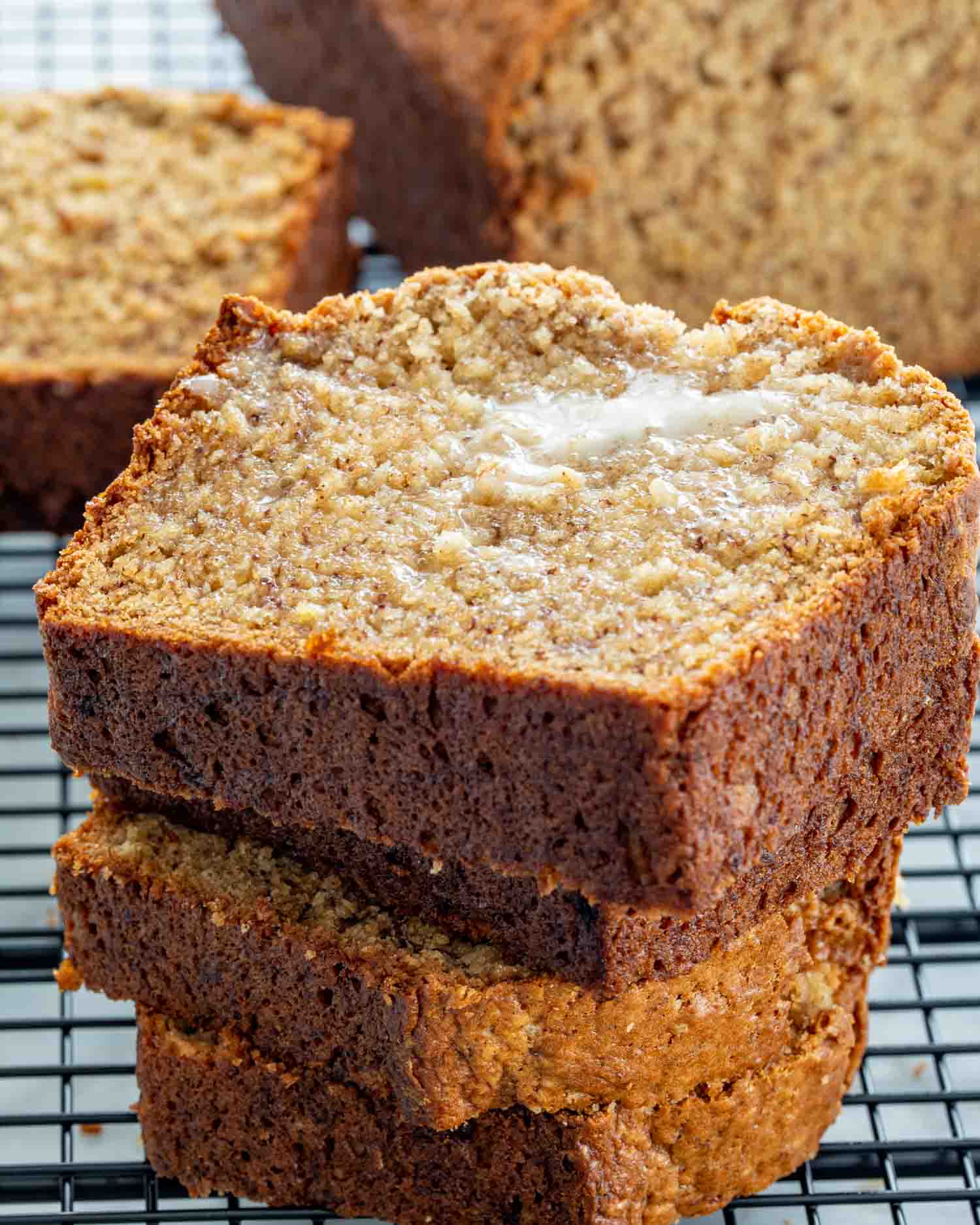 slices of banana bread stacked onto a black cooling rack.
