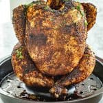 Whole roasted beer can chicken sitting upright in a roasting pan, perfectly golden with herb seasoning.