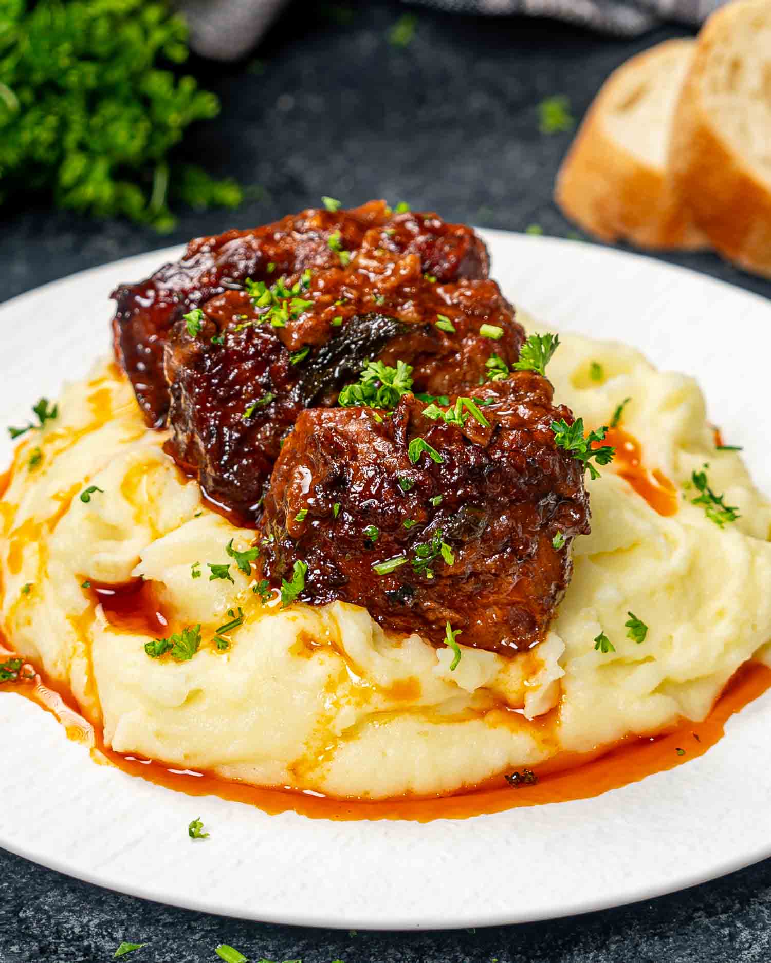 two guinness braised short ribs on a bed of mashed potatoes in a plate.