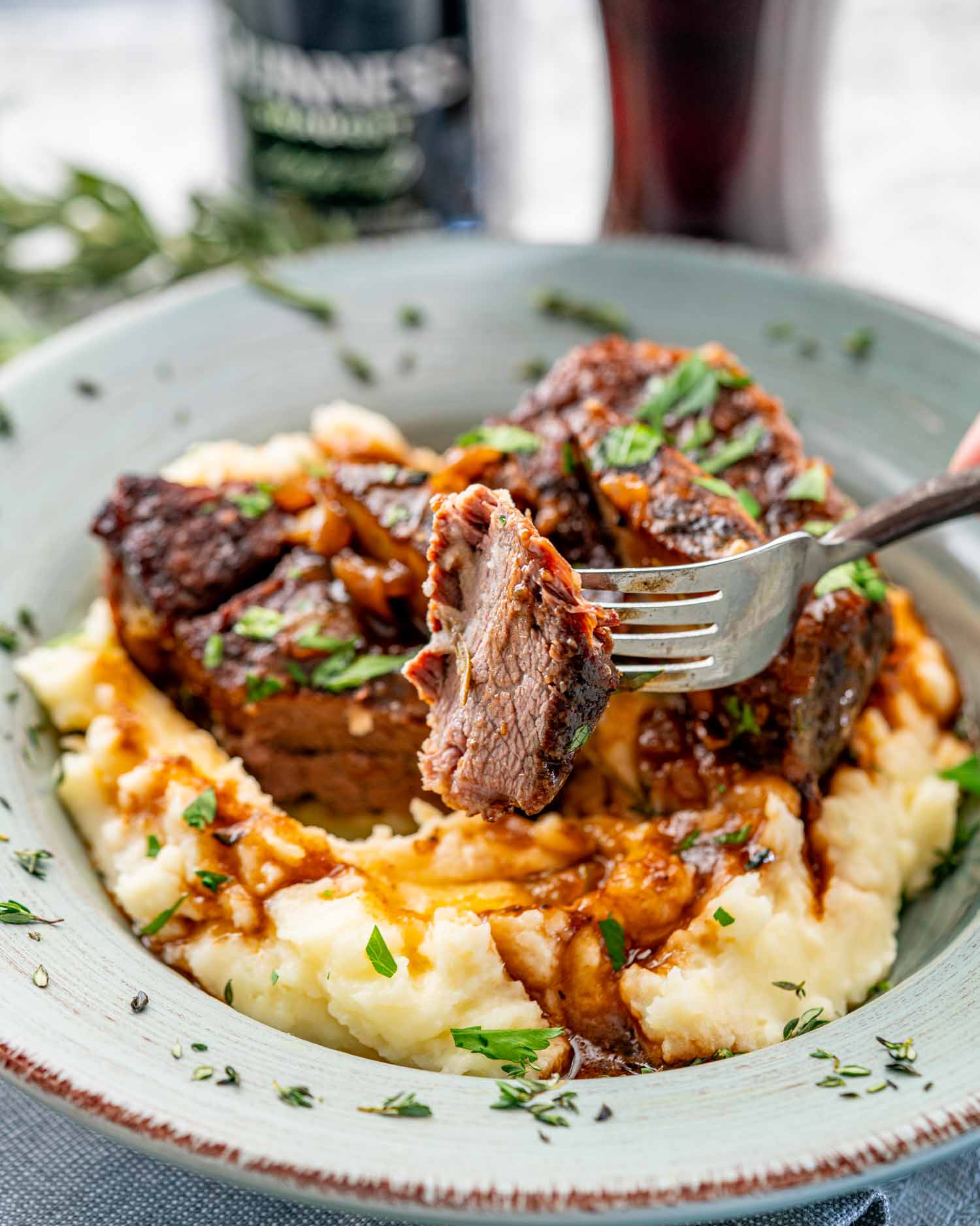 two guinness braised short ribs on a bed of mashed potatoes in a plate.