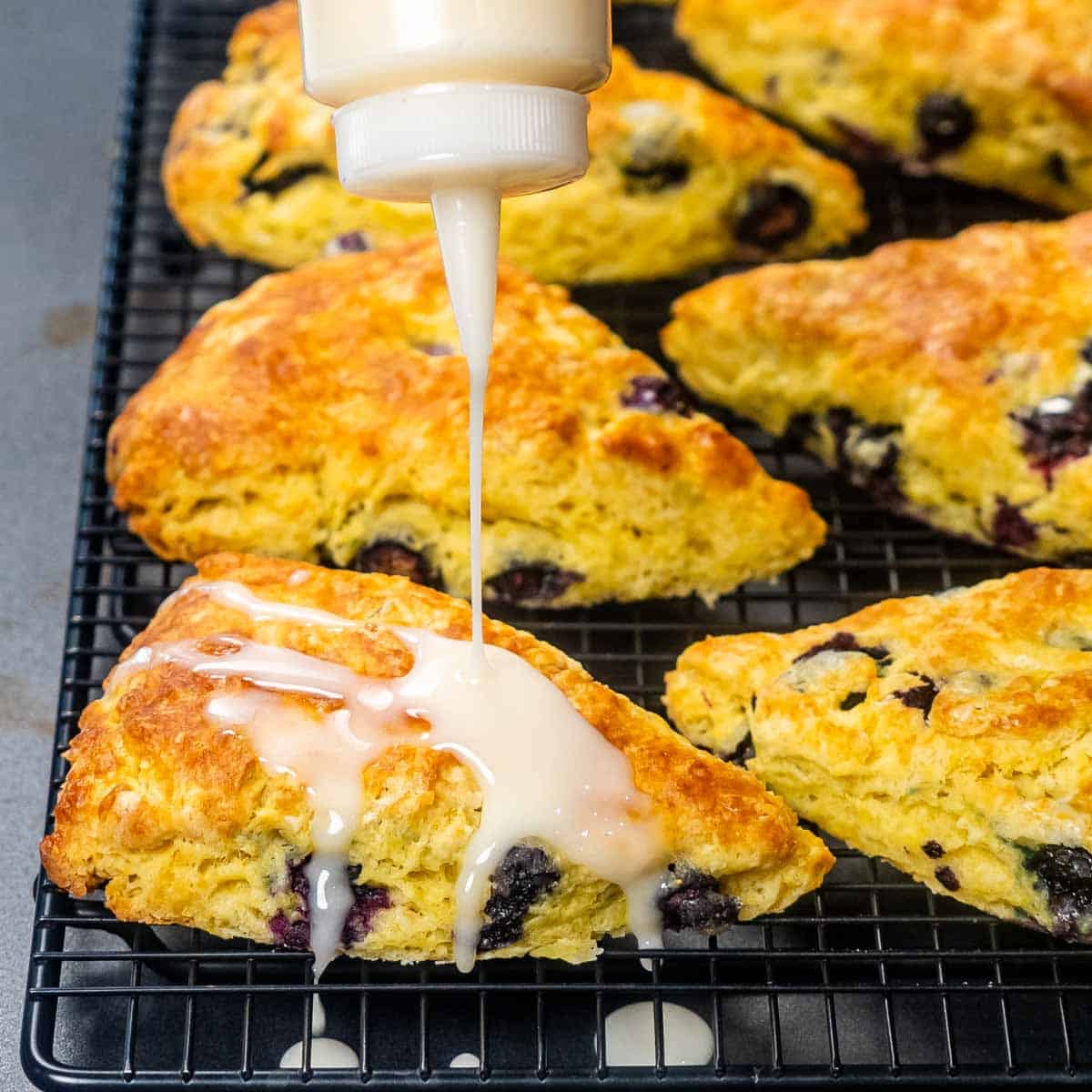 drizzling icing on lemon blueberry scones.