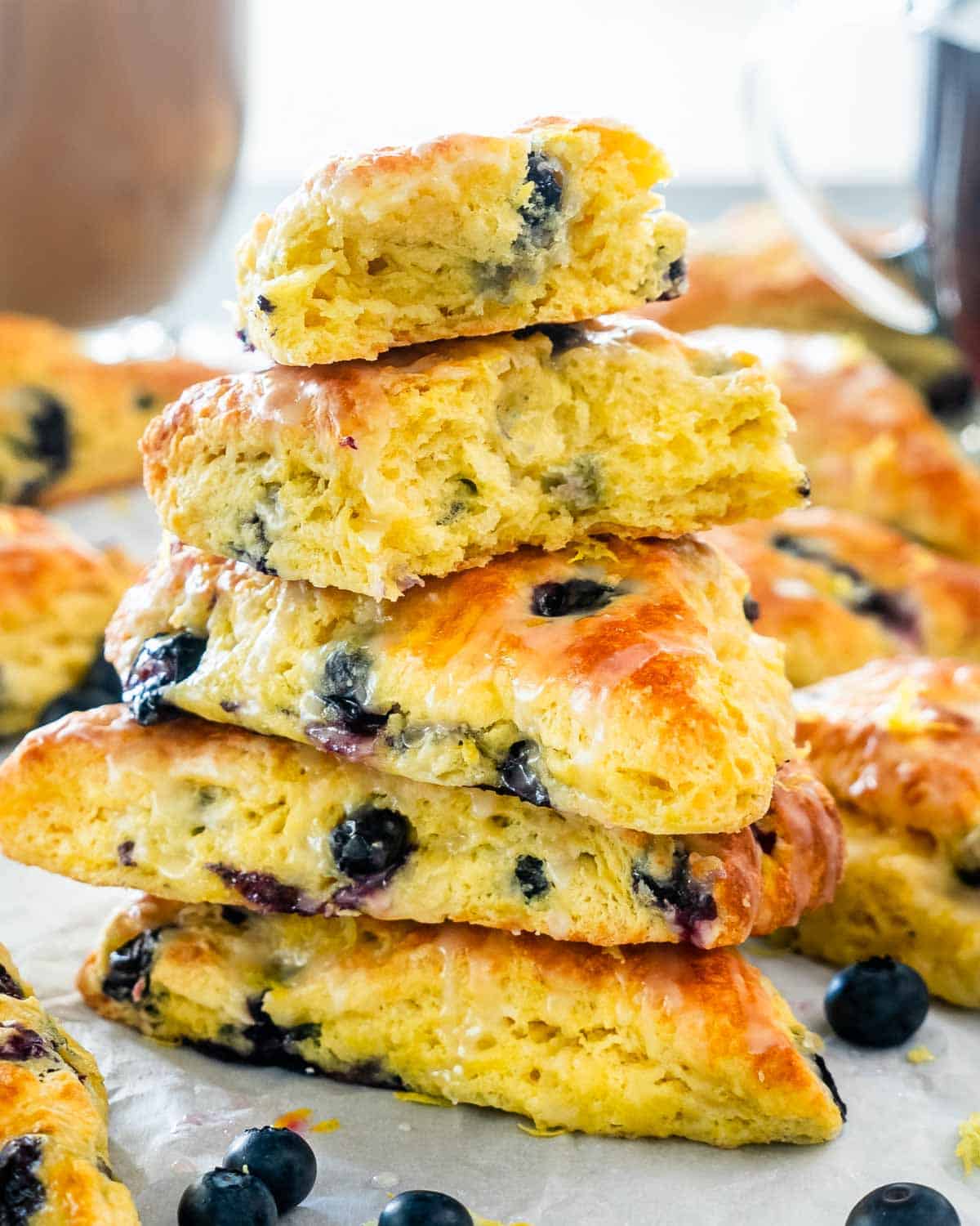 lemon blueberries scones scattered on a table with some blueberries in between.