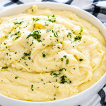 creamy mashed potatoes in a white bowl garnished with parsley.