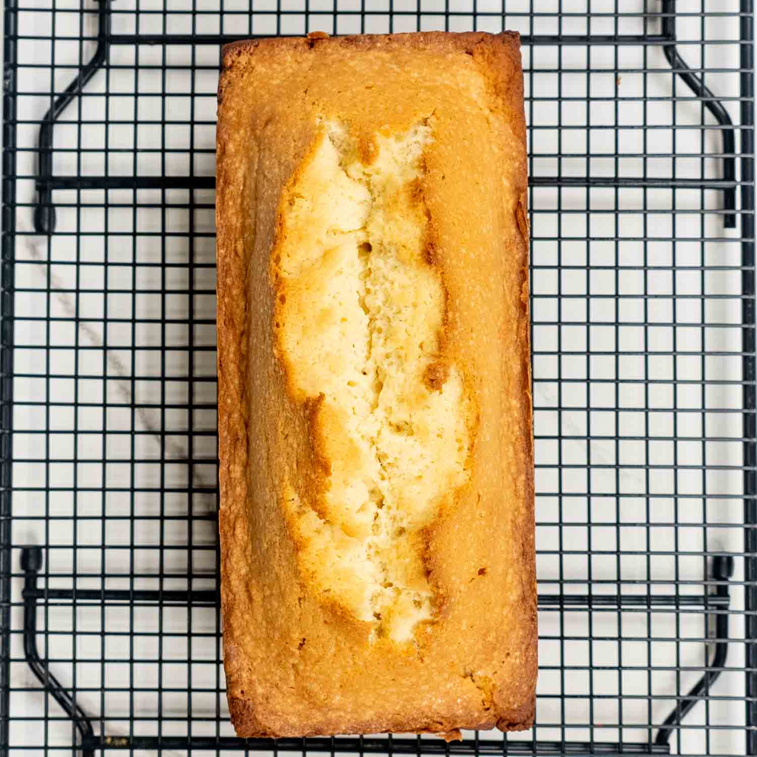 a pound cake cooling on a cooling rack.