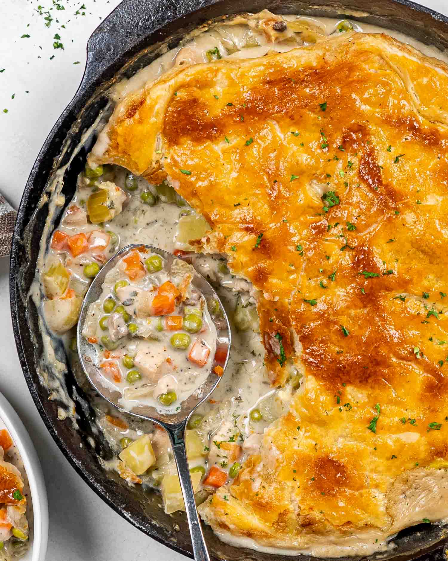skillet chicken pot pie in a cast iron skillet with a serving taken out.