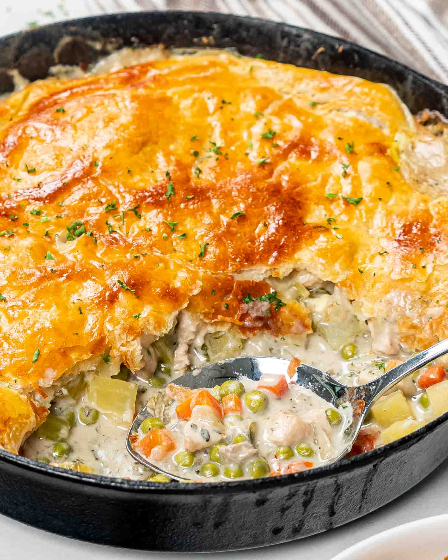 skillet chicken pot pie in a cast iron skillet with a serving taken out.