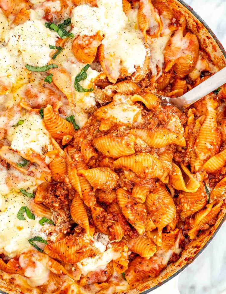 overhead shot of a serving spoon taking a scoop of skillet lasagna.