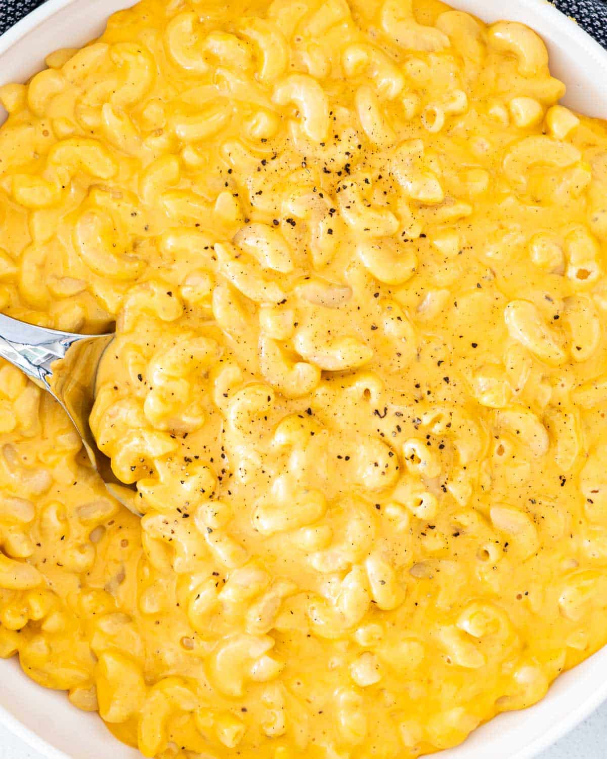 a spoon inside a bowl full of mac and cheese.