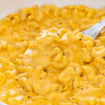 a spoon inside a bowl full of mac and cheese.
