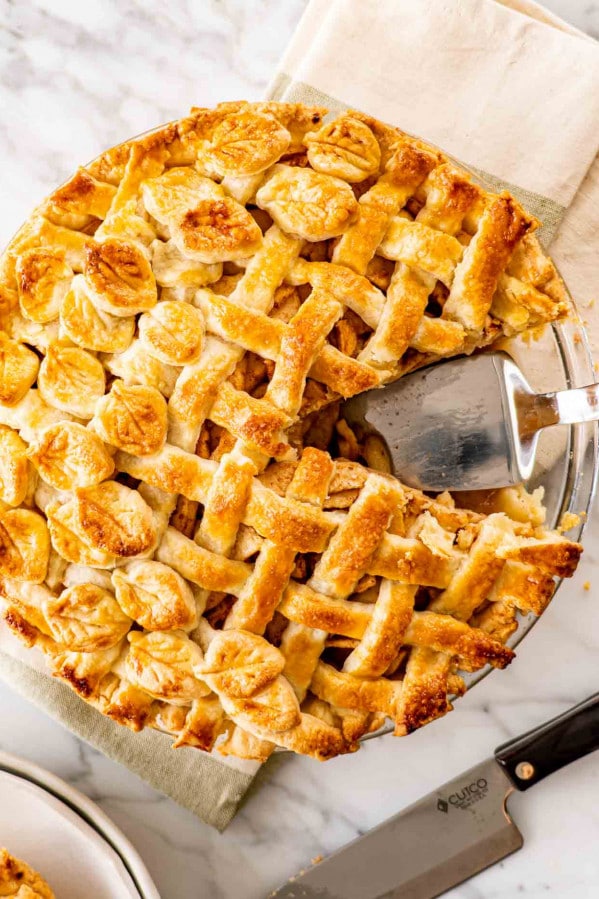 a freshly baked apple pie with lattice top crust and a slice taken out.