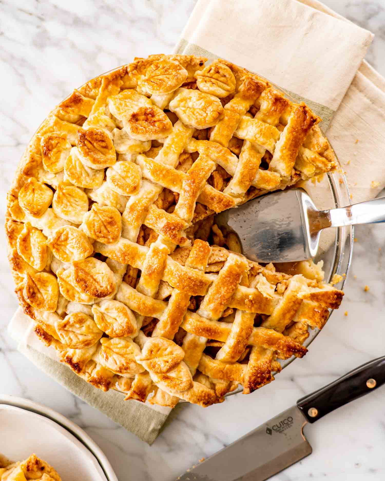 a freshly baked apple pie with lattice top crust and a slice taken out.