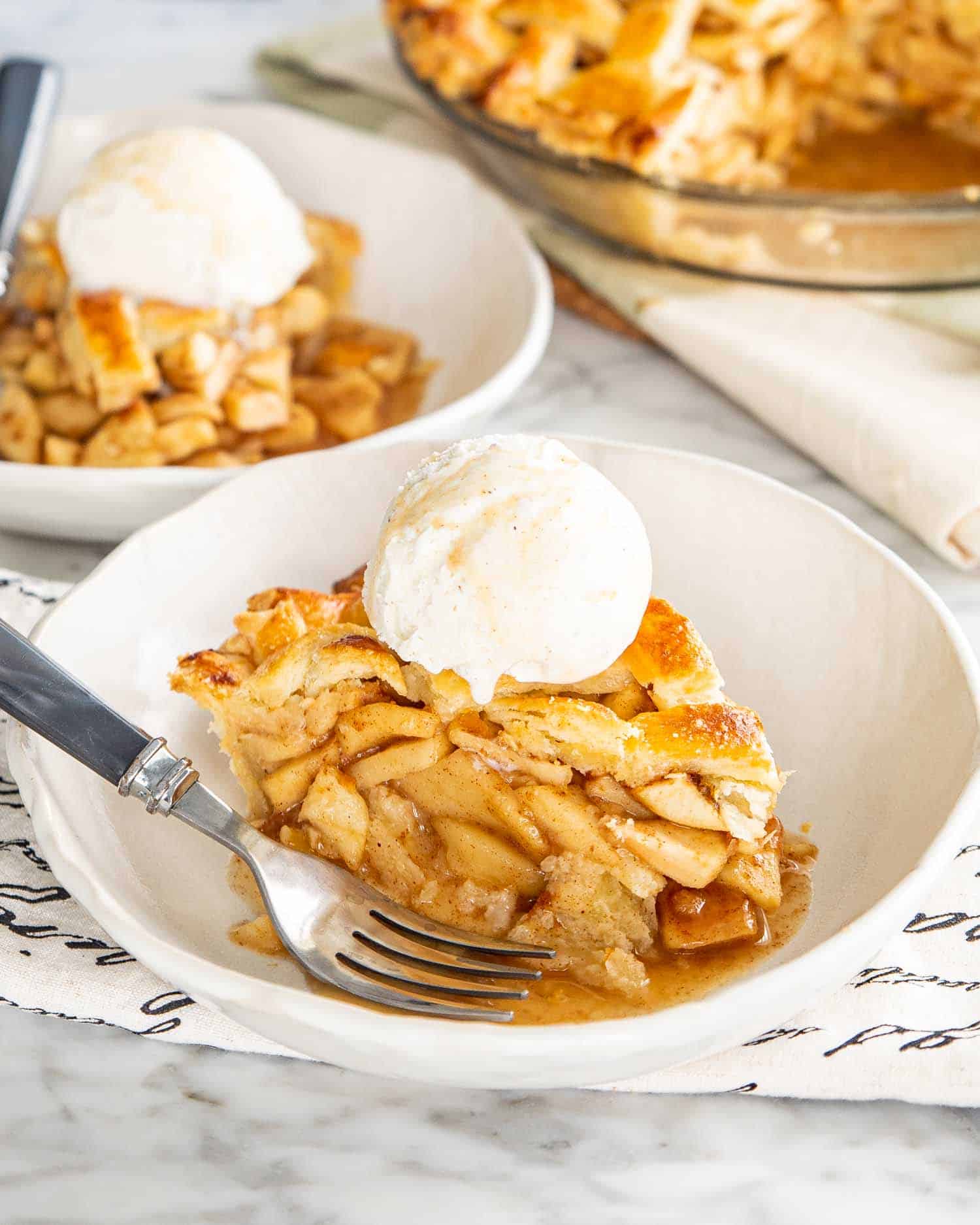 a slice of apple pie with a scoop of ice cream in a bowl.