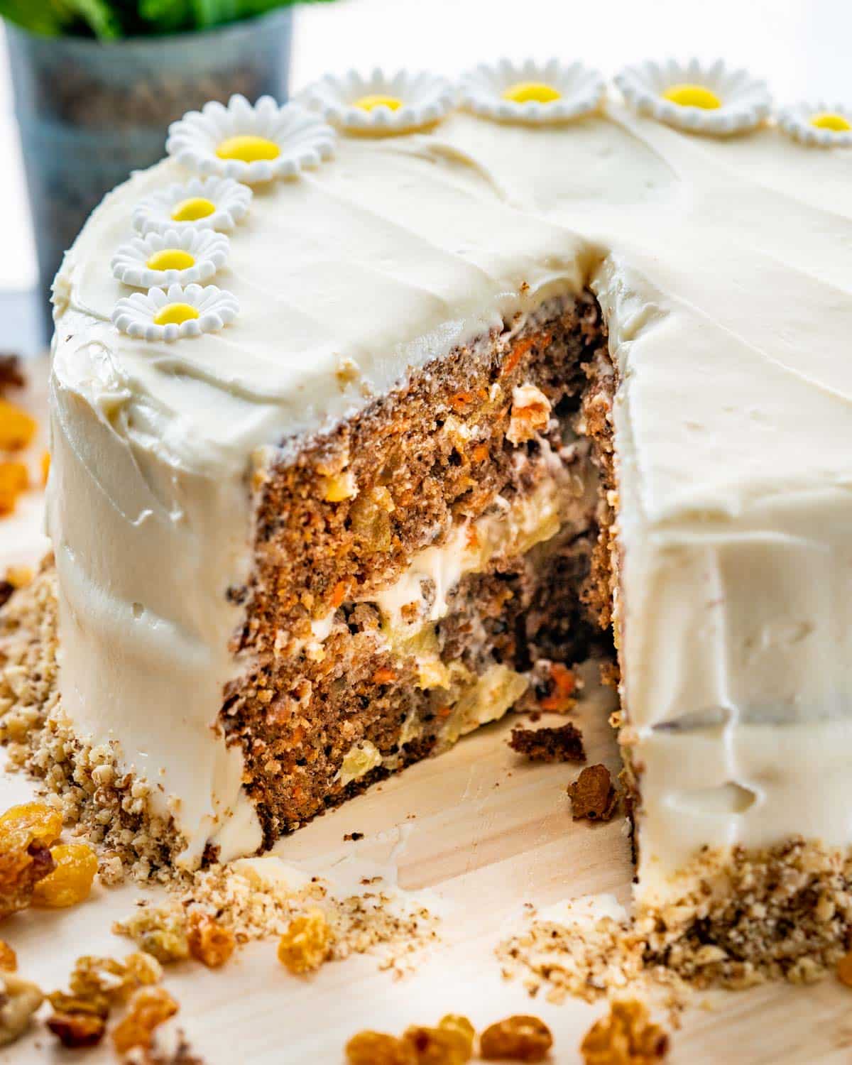a freshly made carrot cake frosted with cream cheese icing and a slice cut out.