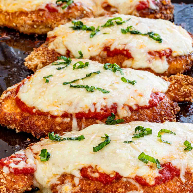 chicken parmesan fresh out of the oven on a baking sheet.