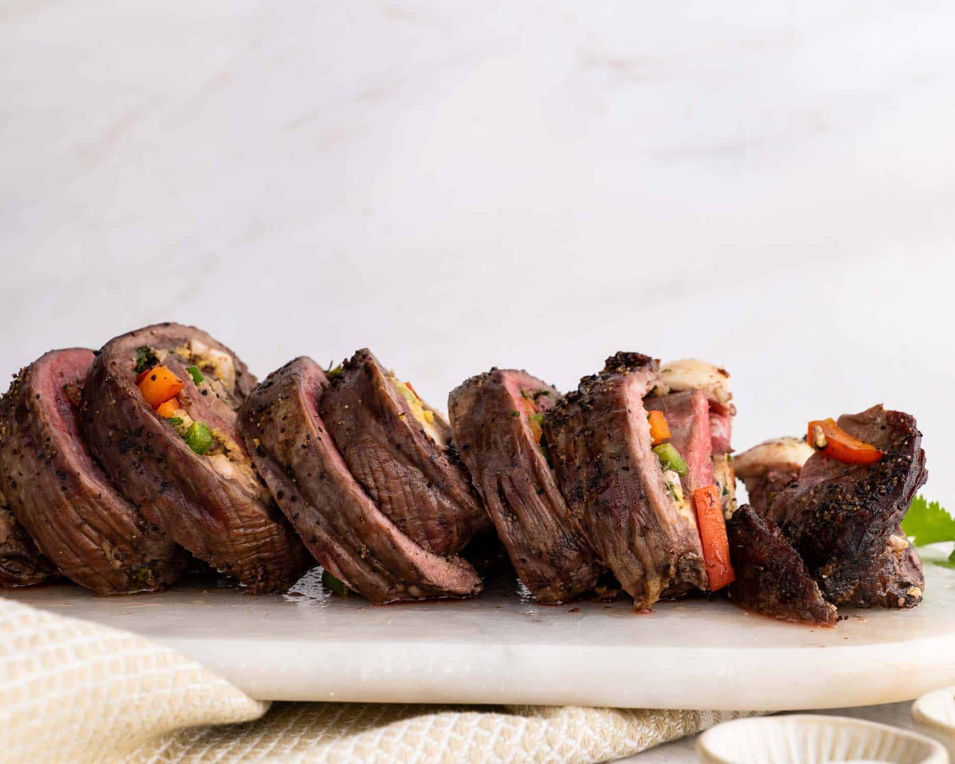 a matambre flank steak cut into slices on a white serving platter.
