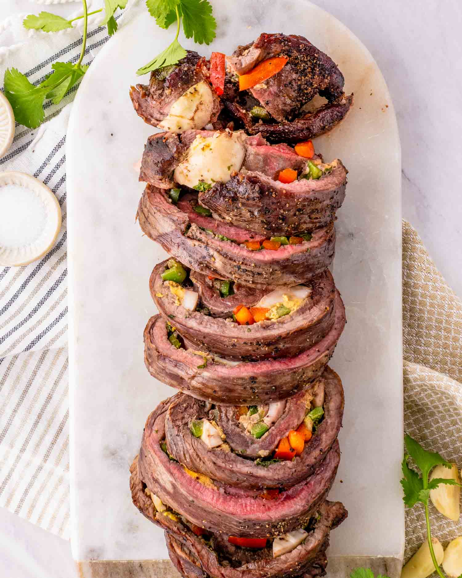 a matambre flank steak cut into slices on a white serving platter.