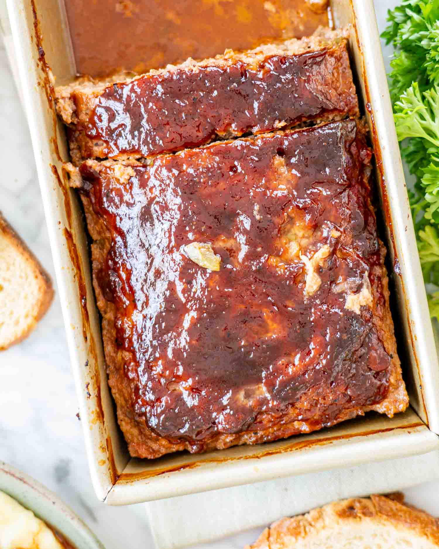 half a meatloaf with bbq sauce left in a loaf pan.