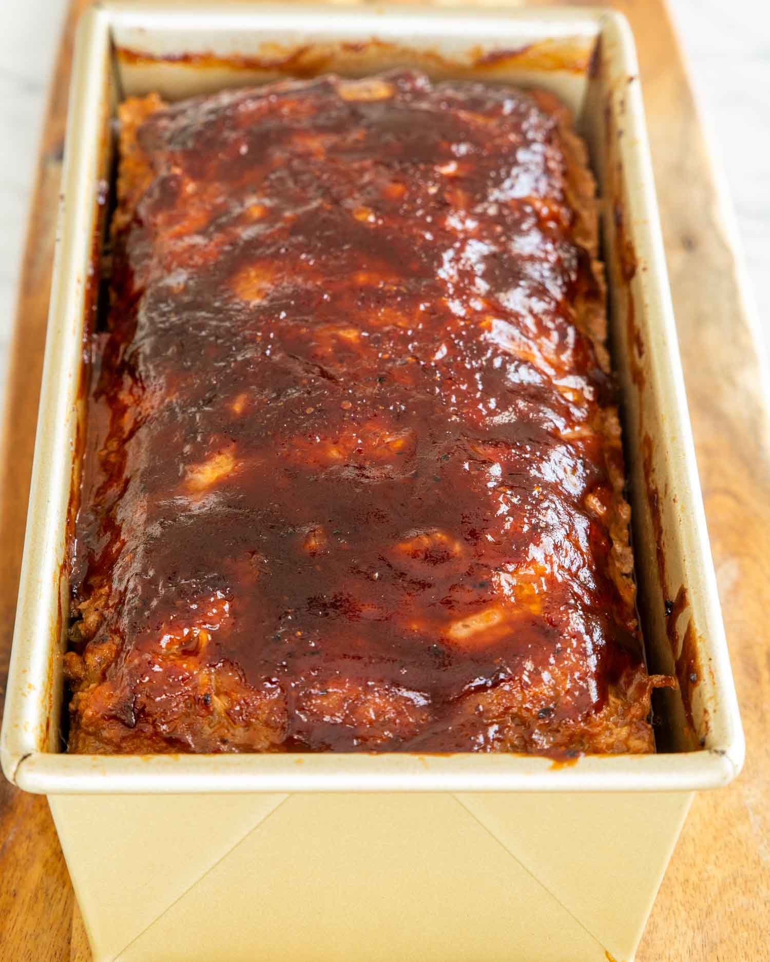 a meatloaf with bbq sauce in a loaf pan fresh out of the oven.