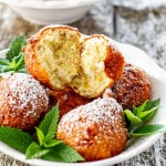 a few banana fritters with mint and sprinkled with powdered sugar in a white bowl.