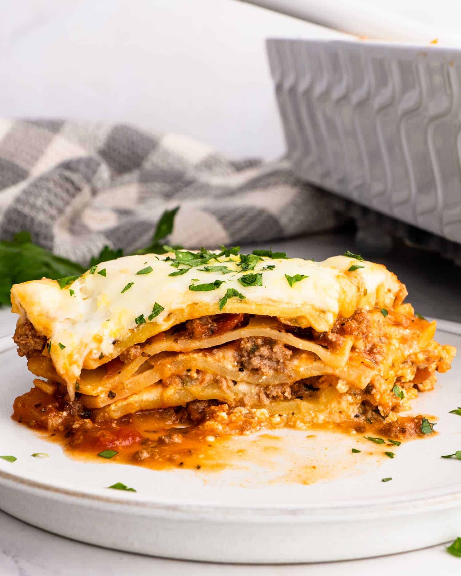 a slice of beef lasagna on a white plate.