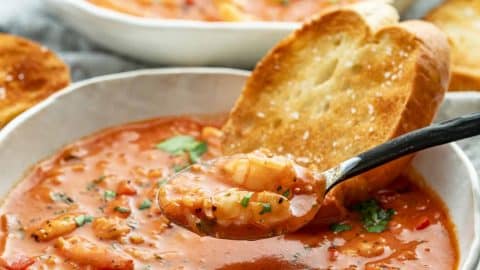 Spoonful of creamy Brazilian shrimp soup with rice, served in a white bowl with toasted bread.
