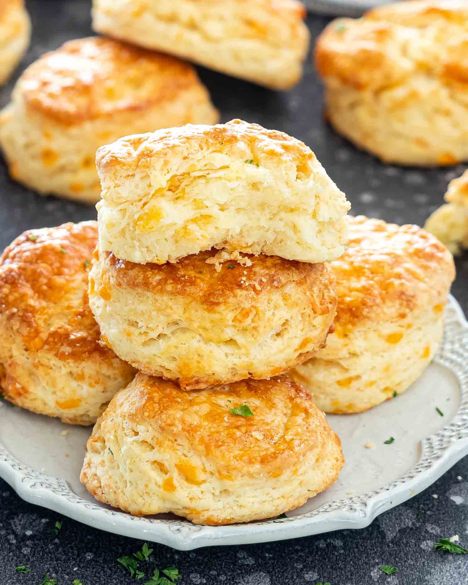 a few cheese biscuits on a beige plate with the top one broken in half.