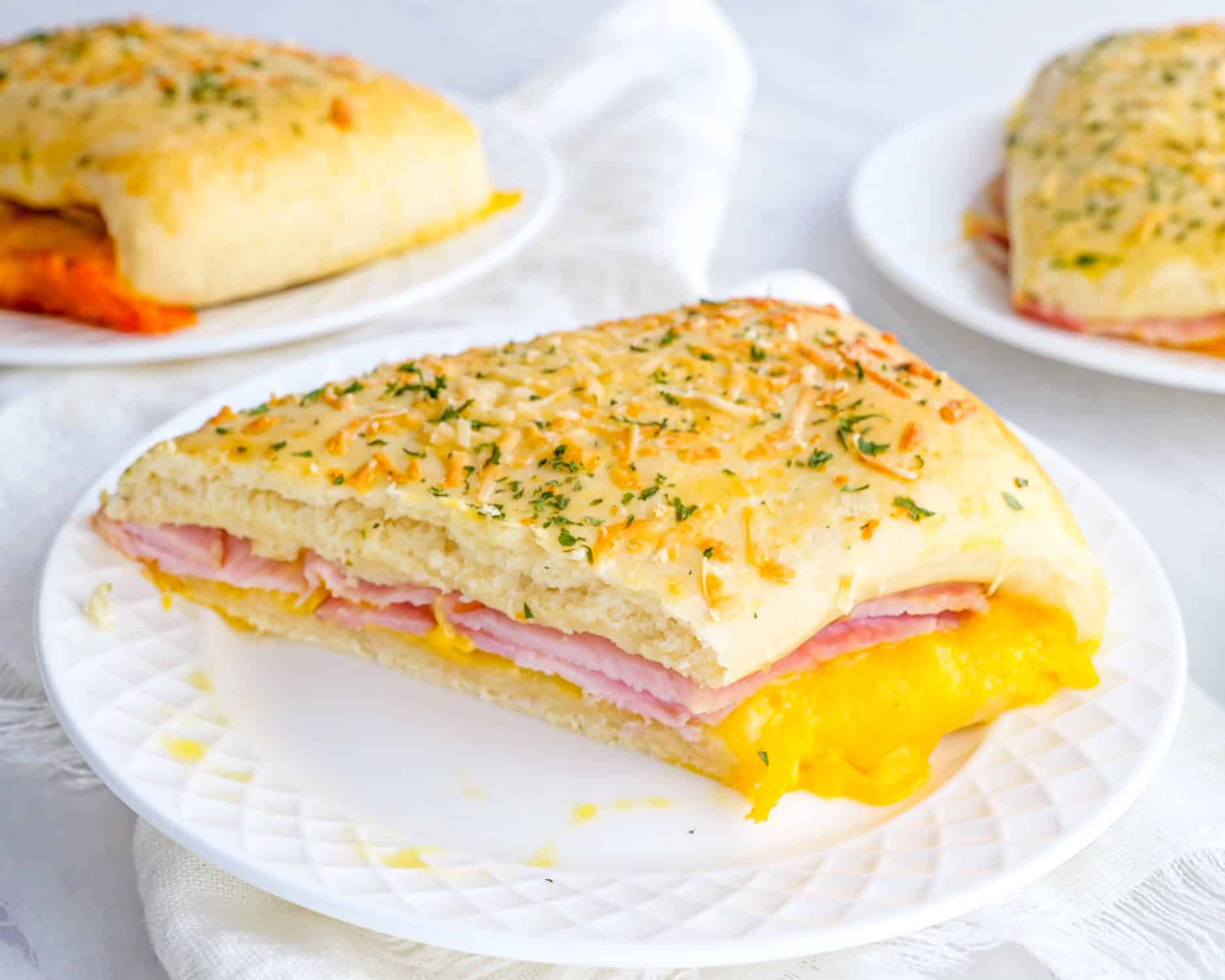 a ham and cheese pocket on a white plate.