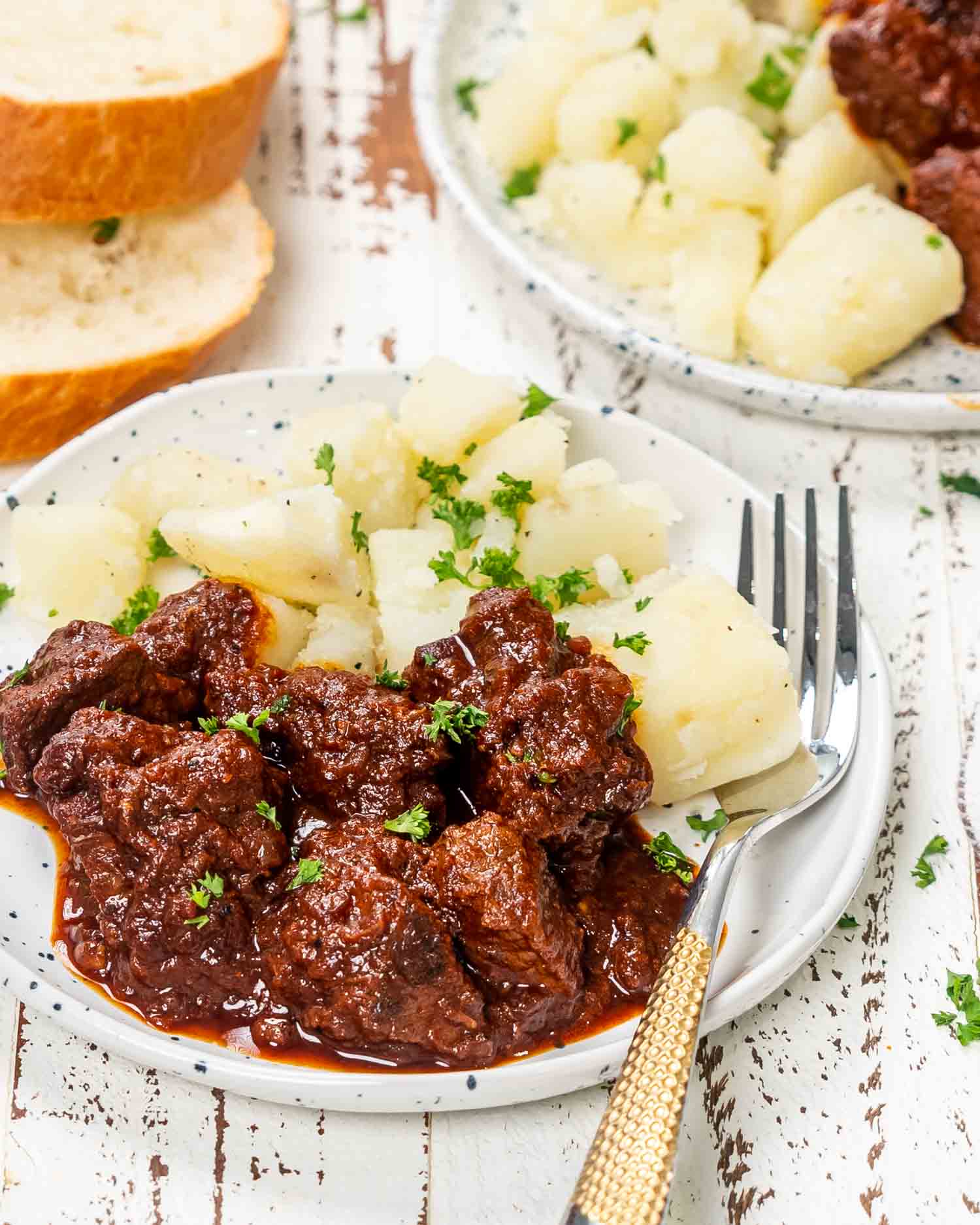 a serving of hungarian goulash with boiled potatoes and garnished with parsley.