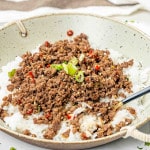 korean beef rice bowl n a beige bowl with a spoon.