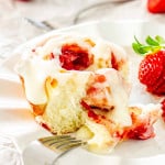 a strawberry roll with cream cheese icing on a white dish.