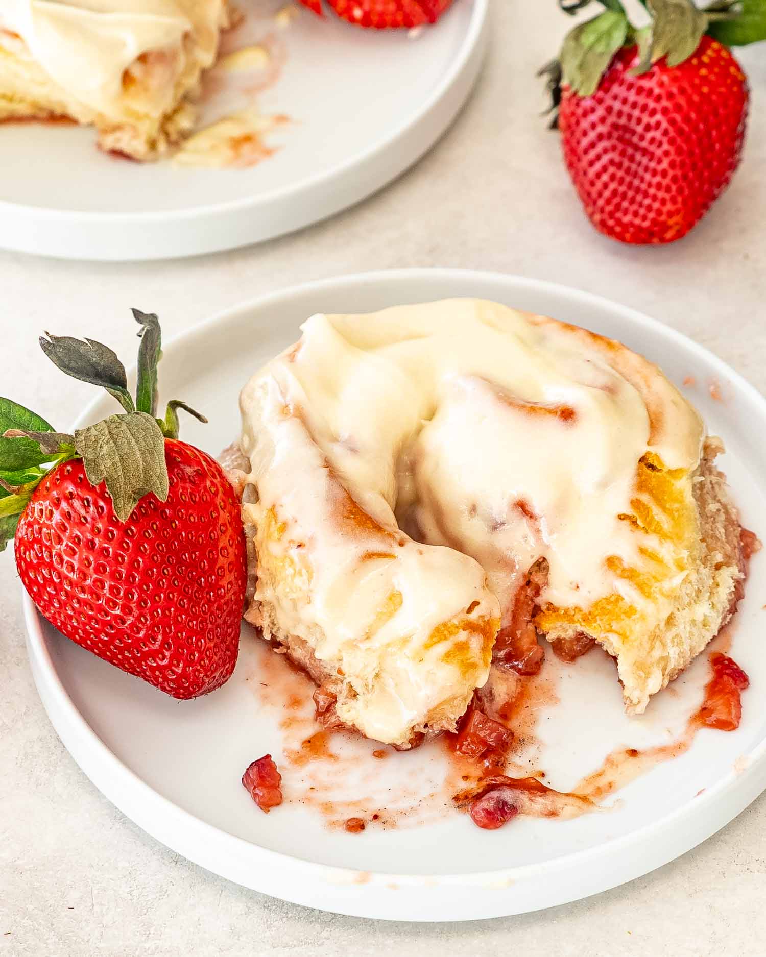 a strawberry roll with cream cheese icing on a white dish.