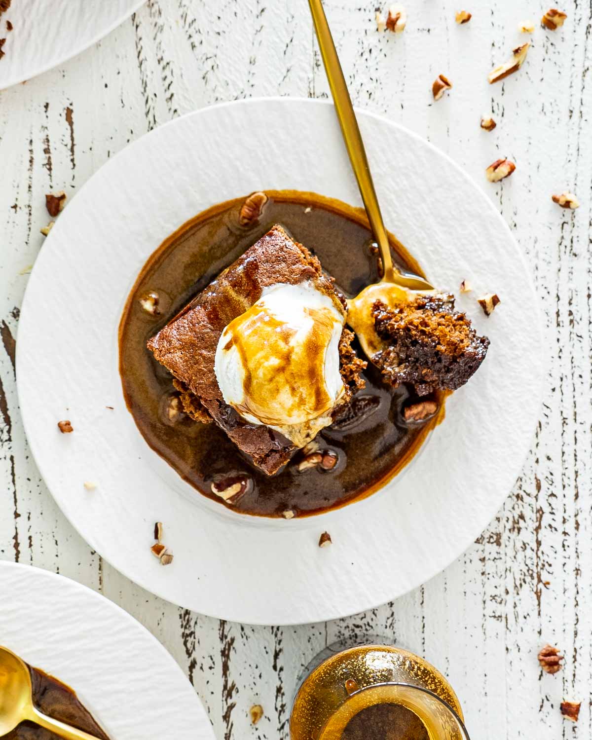 a sticky toffee pudding with an ice cream scoop on top and drizzled with lots of sticky toffee sauce.
