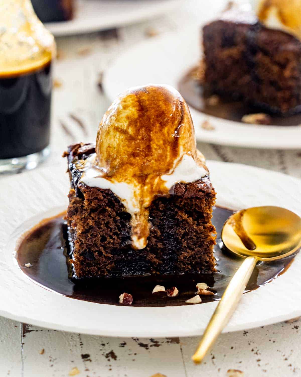 a sticky toffee pudding with an ice cream scoop on top and drizzled with lots of sticky toffee sauce.