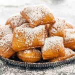 a few beignets with powdered sugar on a plate.