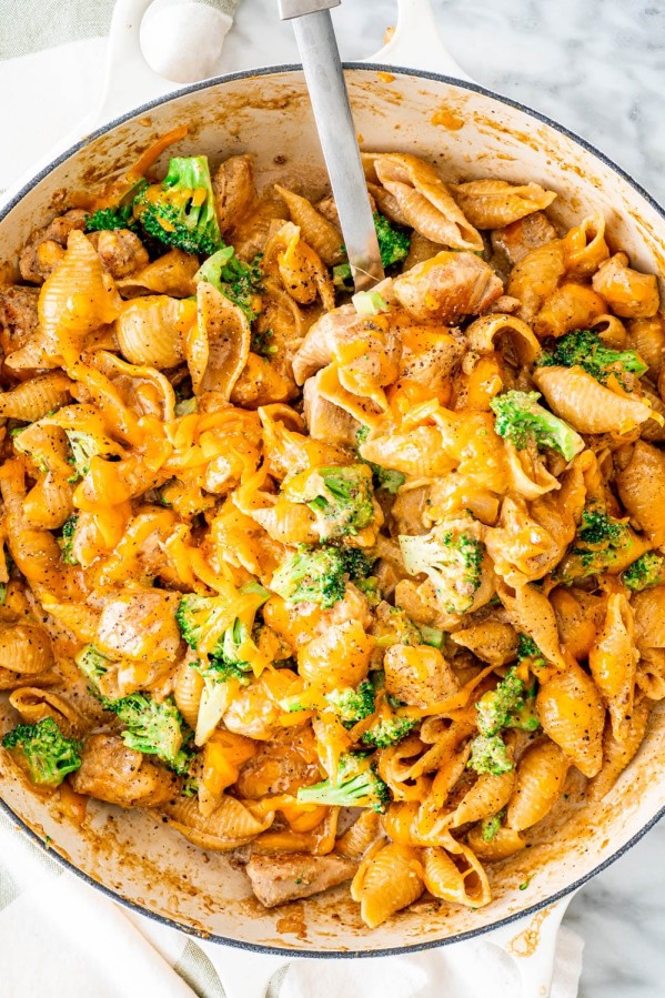 overhead shot of cheesy chicken broccoli pasta in a pot with a serving spoon taking a scoop