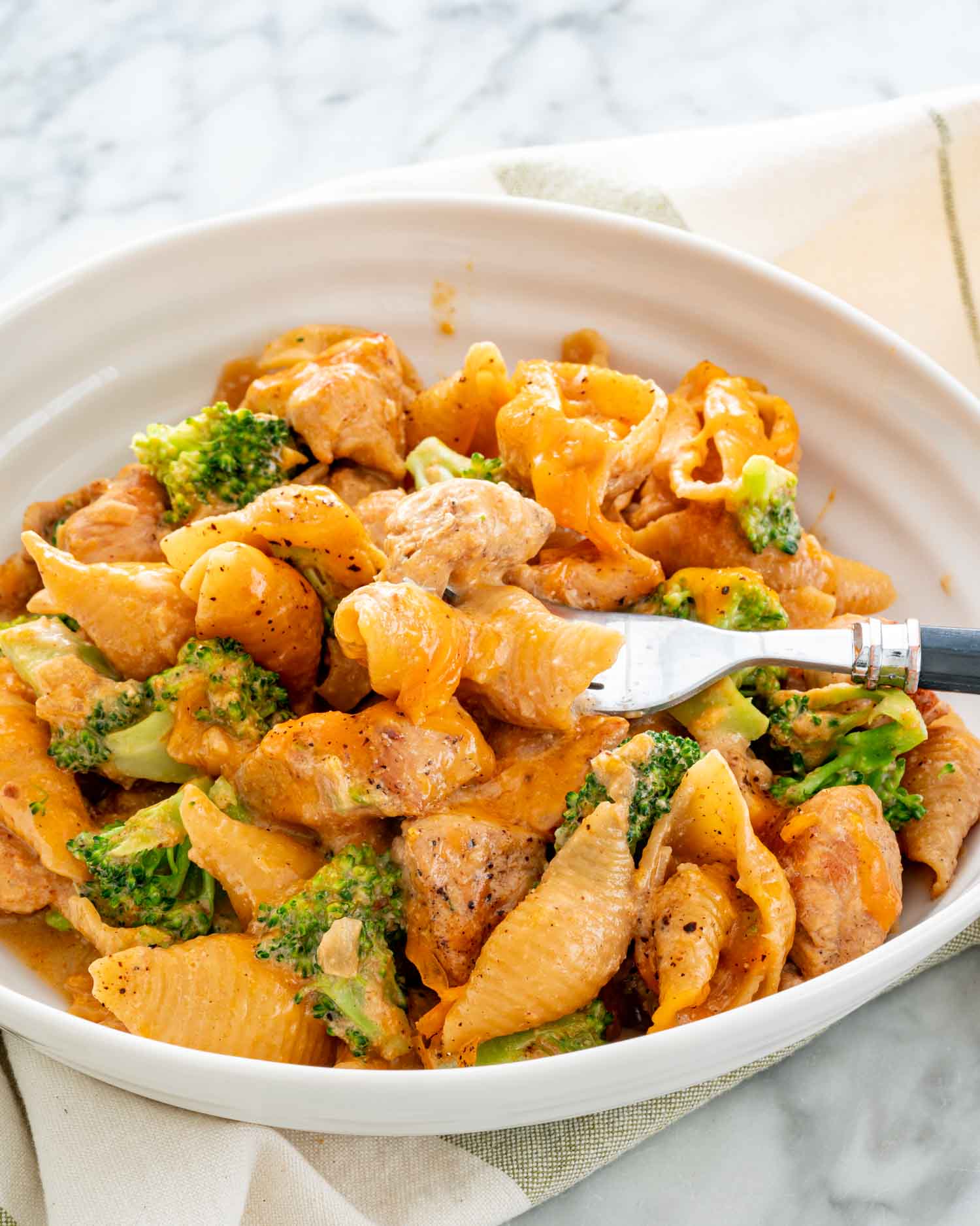 a serving of cheesy chicken broccoli pasta in a white bowl.