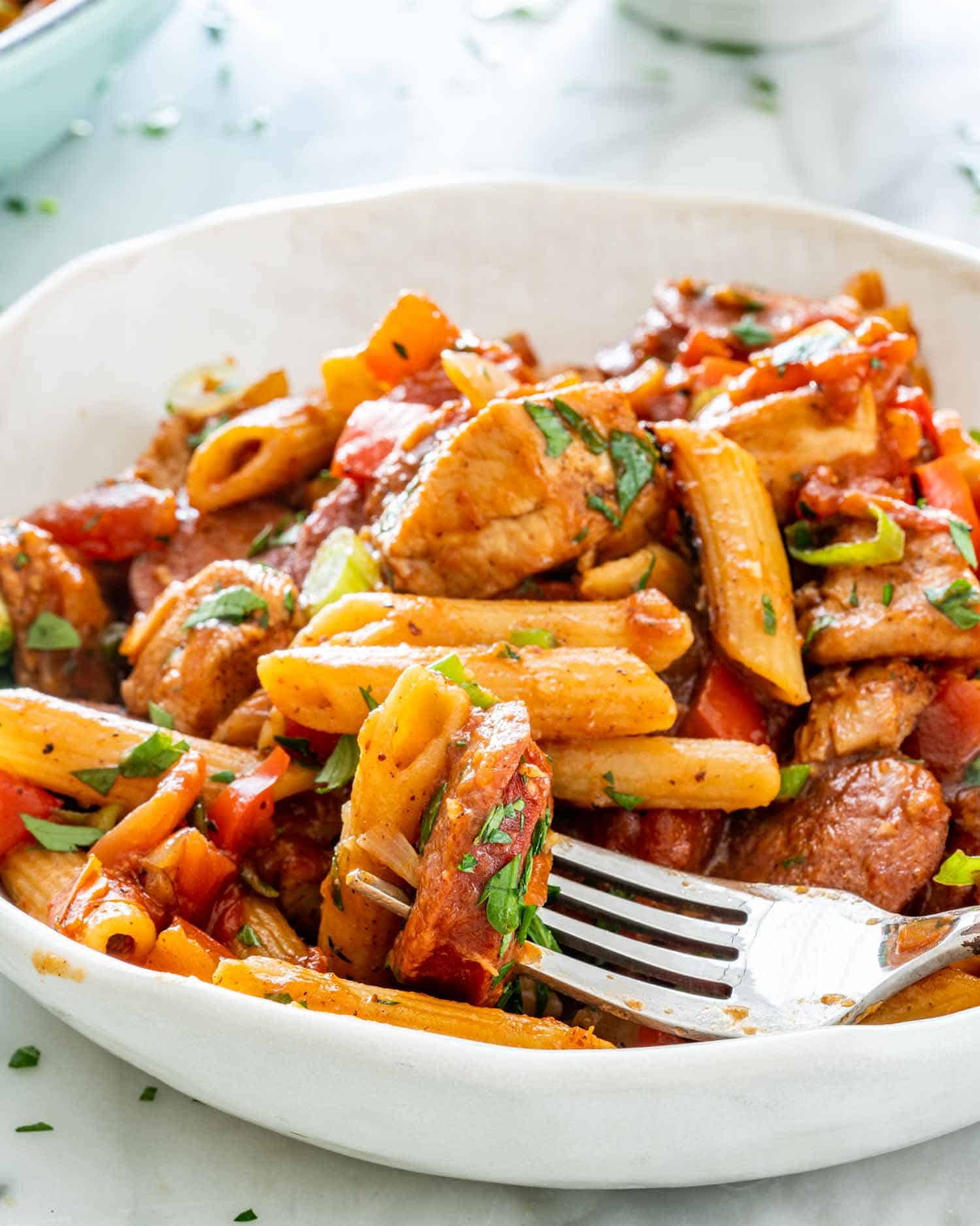 a serving of chicken and sausage penne jambalaya in a white bowl.