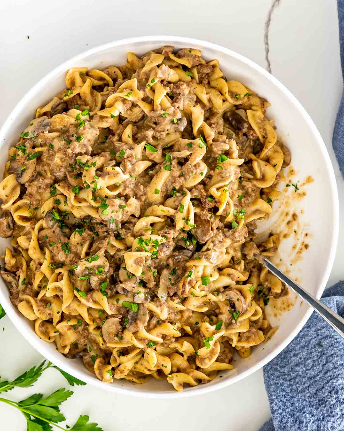 beef stroganoff in a white bowl with a serving spoon.